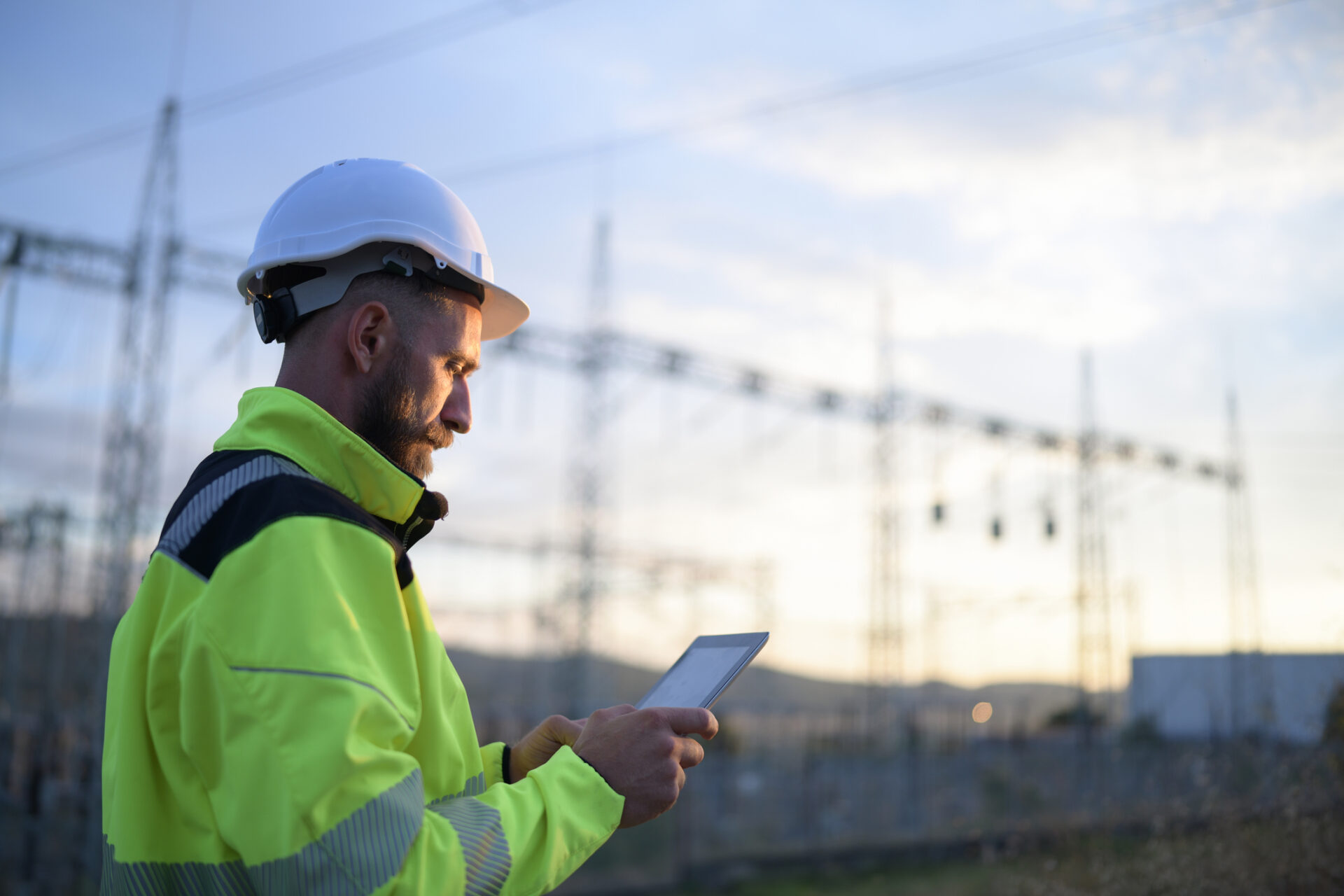 Electrical worker with tablet at a power substation — NFPA 70B compliance software in the field